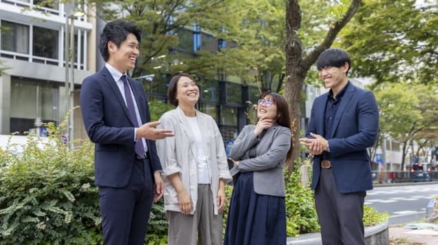 屋外で笑顔で雑談をする4名の男女社員