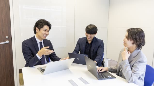 笑顔で会議をする3名の社員