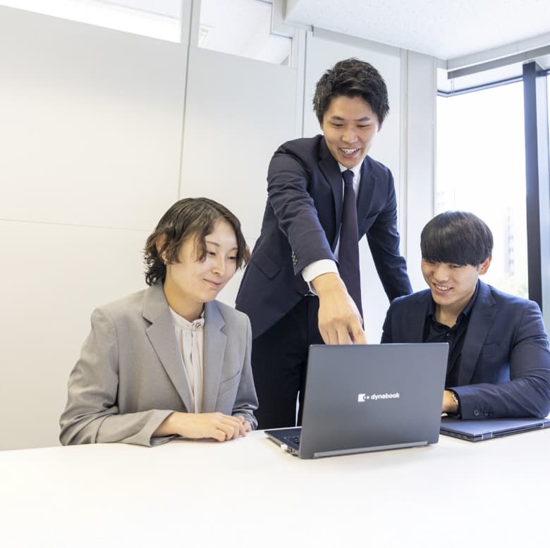 笑顔で仕事の相談をしている3名の社員